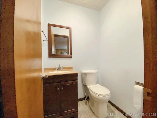 bathroom featuring baseboards, vanity, and toilet