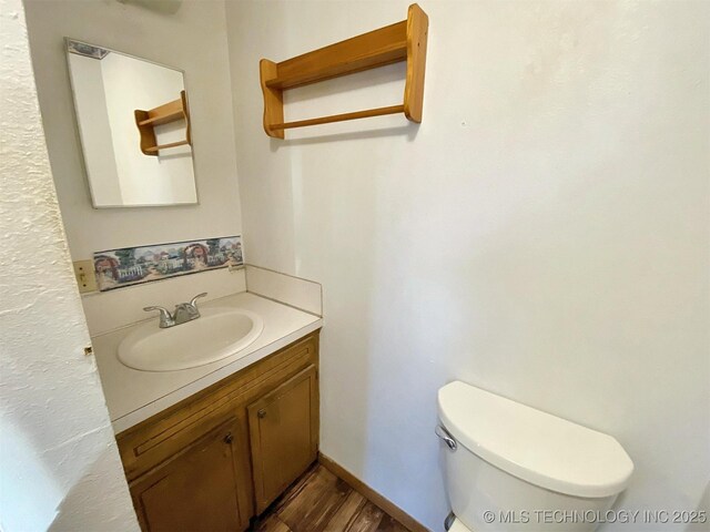 bathroom with wood finished floors, toilet, and vanity