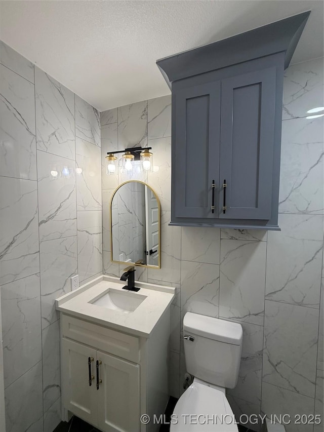 bathroom with tile walls, vanity, a textured ceiling, and toilet