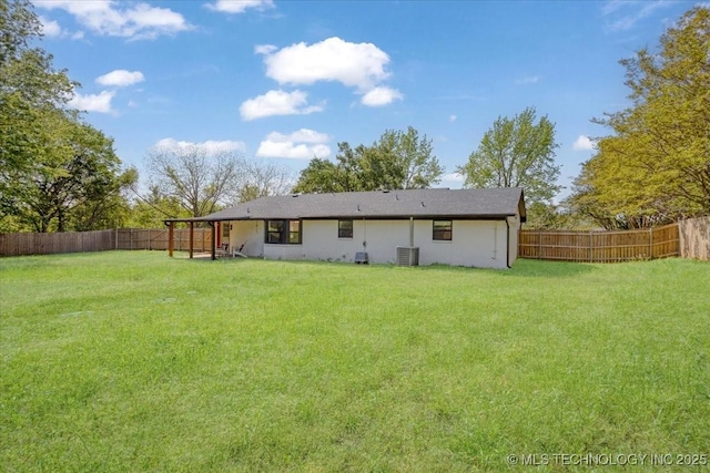 rear view of property featuring a yard, central AC, a fenced backyard, and stucco siding