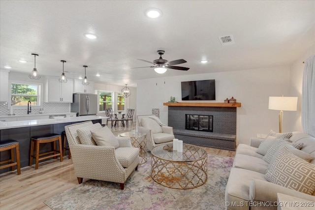 living room featuring recessed lighting, light wood-type flooring, visible vents, and ceiling fan with notable chandelier