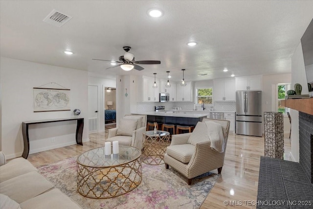 living room with light wood finished floors, a ceiling fan, visible vents, and recessed lighting