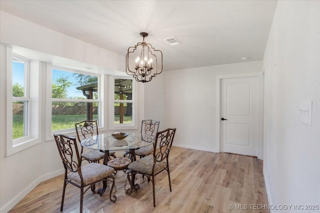 dining space featuring baseboards, a notable chandelier, light wood finished floors, and visible vents