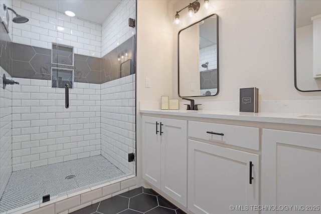 bathroom featuring tile patterned floors, a sink, double vanity, and a stall shower