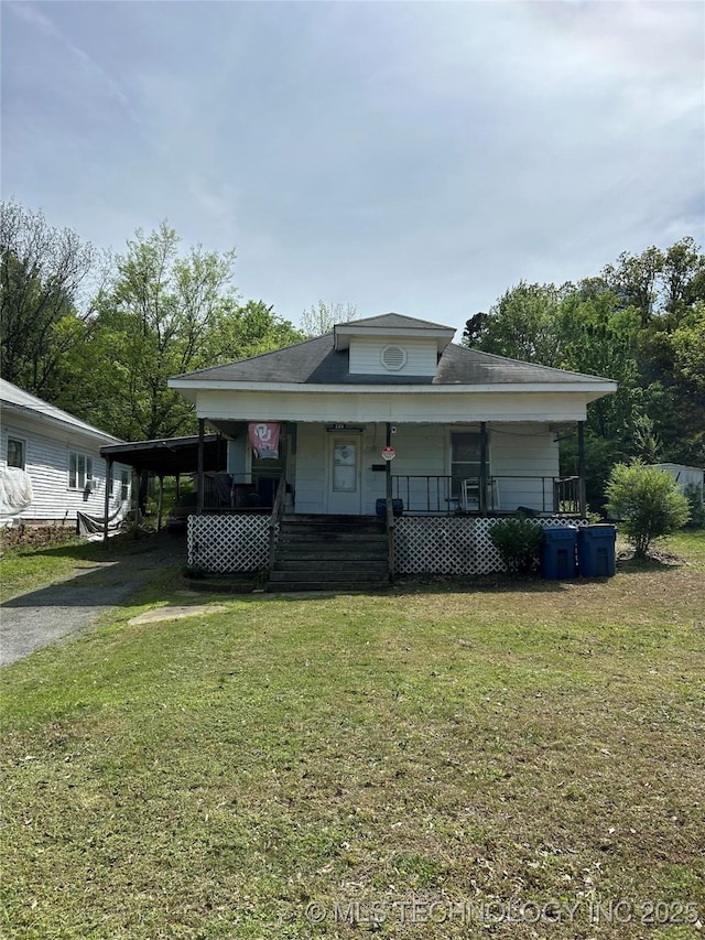 bungalow featuring aphalt driveway, a front lawn, covered porch, and an attached carport