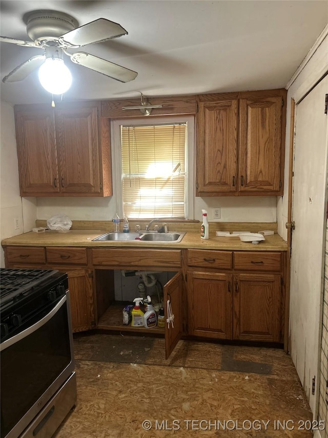 kitchen featuring stainless steel range with gas cooktop, brown cabinets, ceiling fan, and light countertops