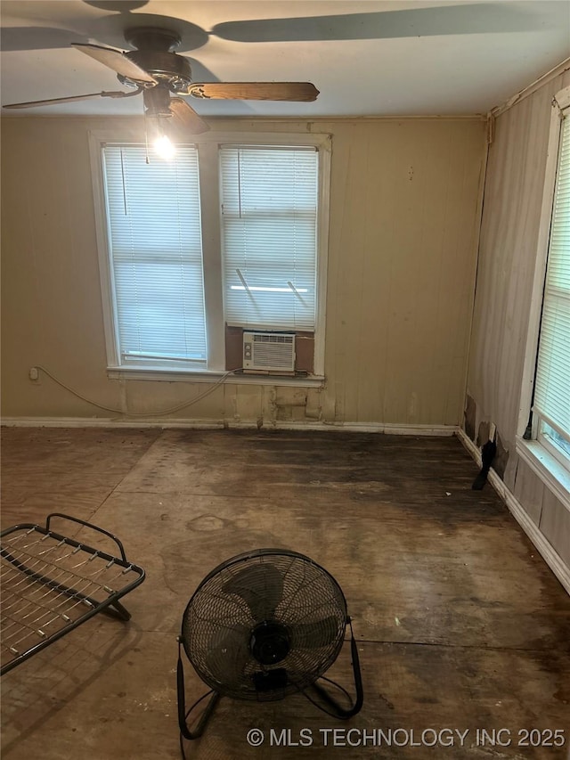 empty room featuring ceiling fan, baseboards, wooden walls, and cooling unit
