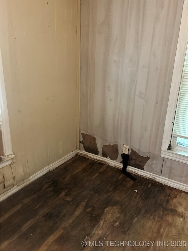 empty room featuring baseboards and dark wood-type flooring