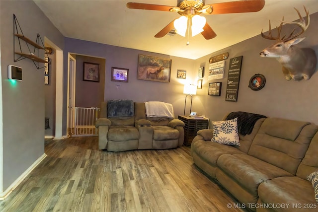 living room featuring baseboards, a ceiling fan, and wood finished floors