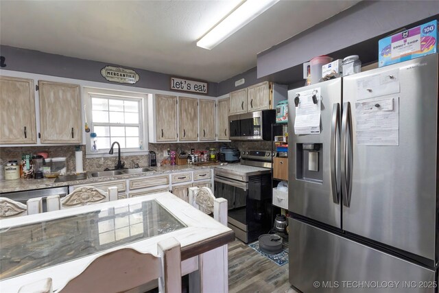 kitchen featuring stainless steel appliances, a sink, backsplash, wood finished floors, and light countertops