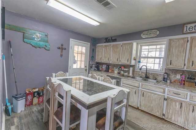 kitchen with light wood-style flooring, a sink, tasteful backsplash, visible vents, and light brown cabinets
