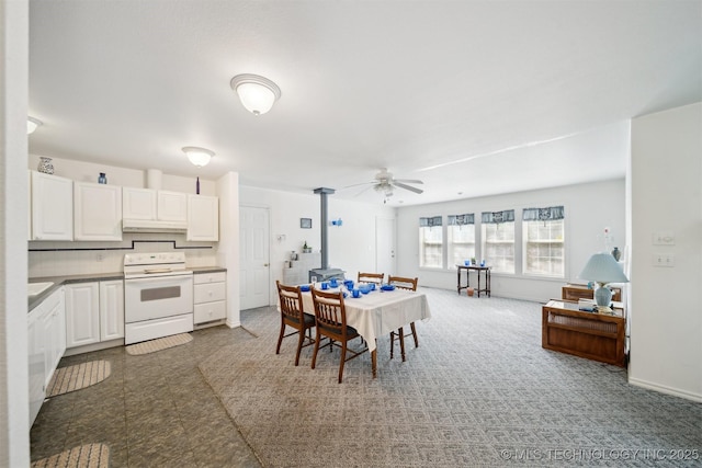 857 Bayshore Dr, Sand Springs, OK 74063 - dining room featuring a wood stove, ceiling fan, baseboards, and carpet