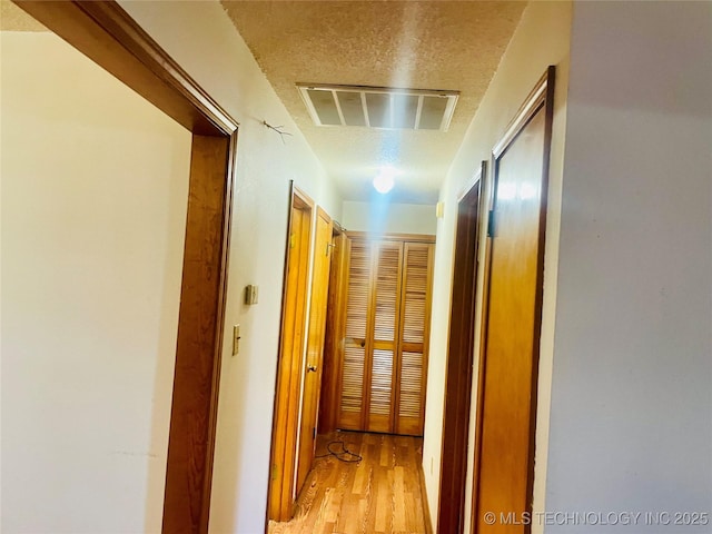 109 Ash Ave, Fort Gibson, OK 74434 - hallway with a textured ceiling, light wood-style flooring, and visible vents