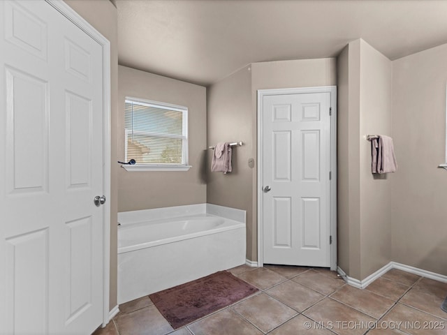 full bathroom with a bath, tile patterned floors, and baseboards