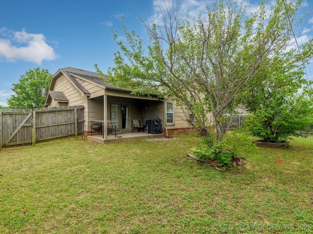 back of property with a patio, a yard, and a fenced backyard