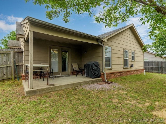 rear view of property with a lawn, a patio, and a fenced backyard