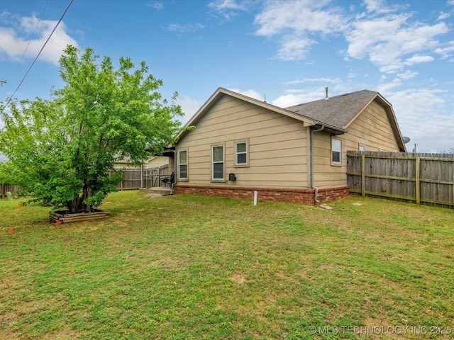 rear view of house featuring fence and a lawn