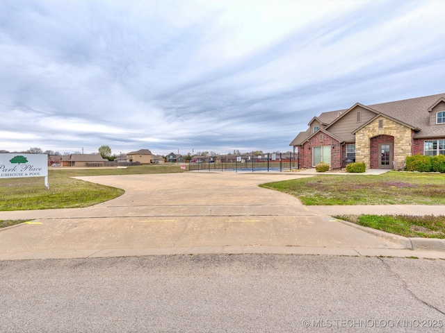 view of front of house featuring a front yard, brick siding, stone siding, and fence