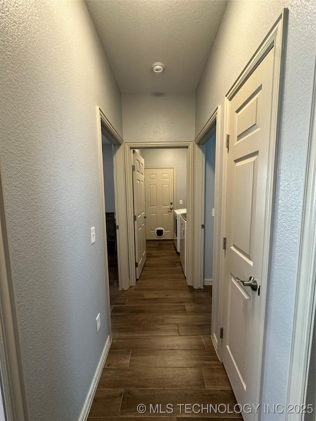corridor with baseboards, a textured wall, a textured ceiling, and dark wood-style floors