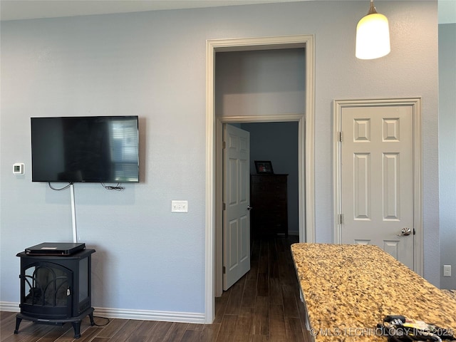 interior space featuring dark wood finished floors, baseboards, and a wood stove
