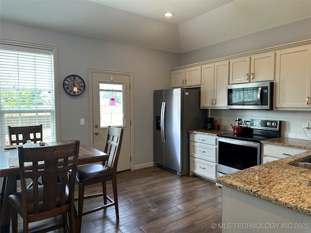 kitchen with white cabinets, stainless steel appliances, dark wood-type flooring, light stone countertops, and tasteful backsplash