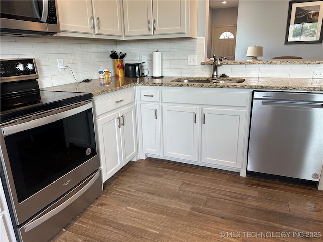 kitchen with a sink, white cabinetry, decorative backsplash, light stone counters, and appliances with stainless steel finishes