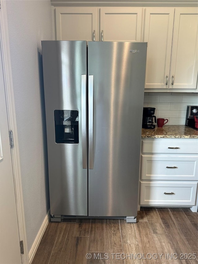 kitchen with stainless steel refrigerator with ice dispenser, stone countertops, tasteful backsplash, and dark wood finished floors