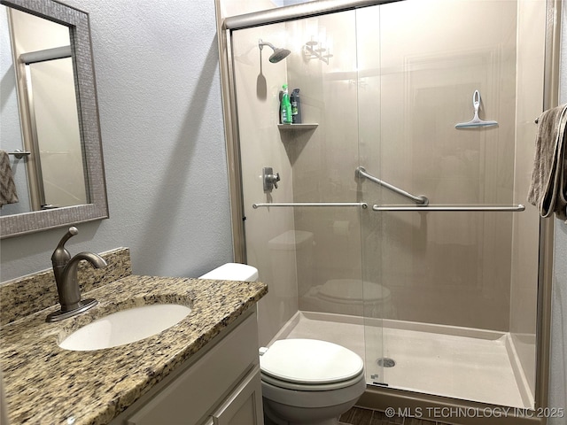 full bath featuring a shower stall, toilet, vanity, and a textured wall