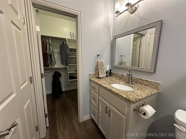 bathroom featuring baseboards, wood finished floors, vanity, and toilet