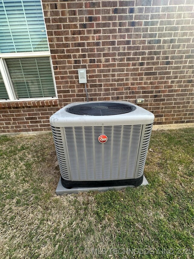 exterior details featuring central AC and brick siding