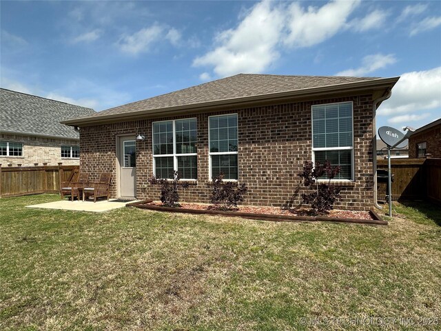 back of house with brick siding, a lawn, a patio, and fence