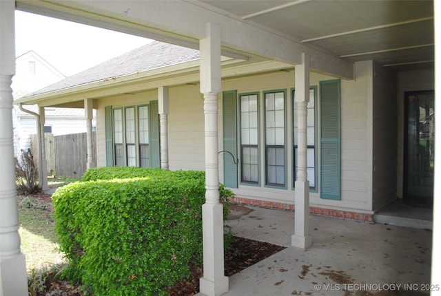 property entrance with covered porch and fence