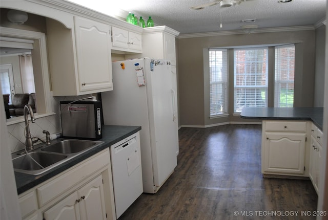 kitchen with dark countertops, white appliances, and a sink
