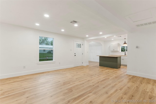 unfurnished living room featuring light wood finished floors, baseboards, visible vents, and recessed lighting