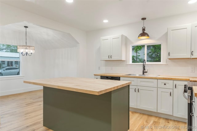 kitchen with wood counters, tasteful backsplash, a sink, and light wood-style floors