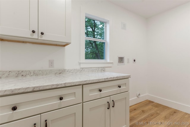interior space featuring electric dryer hookup, cabinet space, washer hookup, light wood-type flooring, and baseboards
