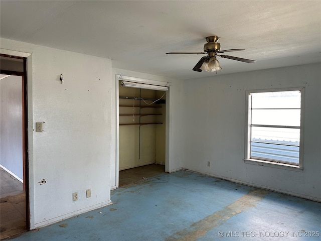 unfurnished bedroom featuring concrete floors, baseboards, a ceiling fan, and a closet