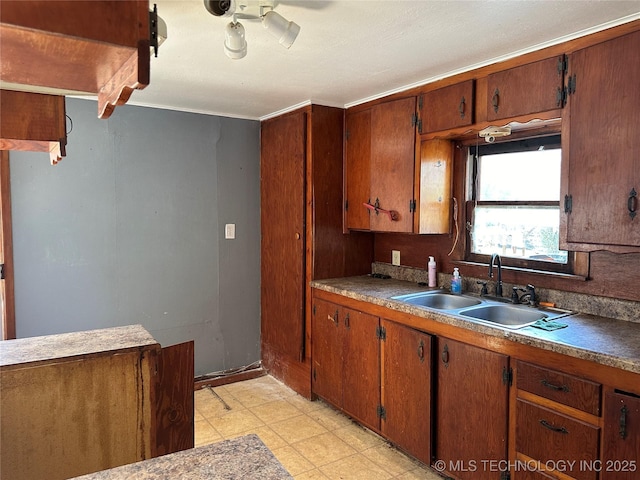 kitchen with light floors, brown cabinetry, a sink, and ceiling fan