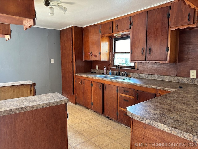 kitchen with light floors, brown cabinetry, and a sink