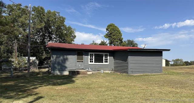 back of property with fence, a yard, and metal roof