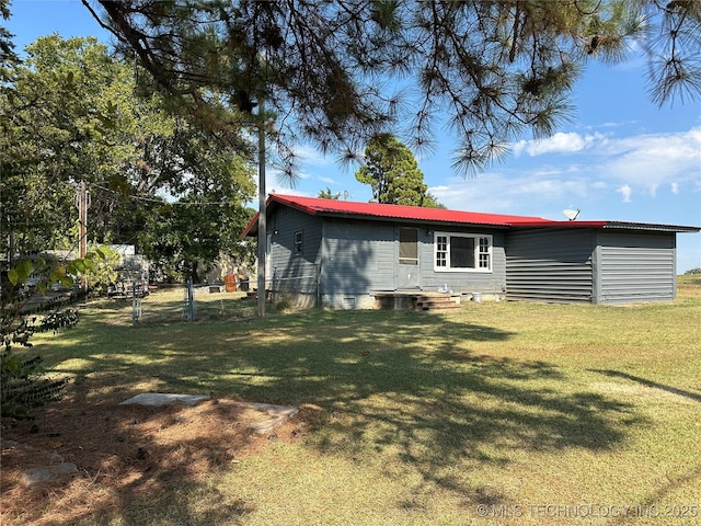 rear view of property featuring metal roof, a lawn, crawl space, and fence