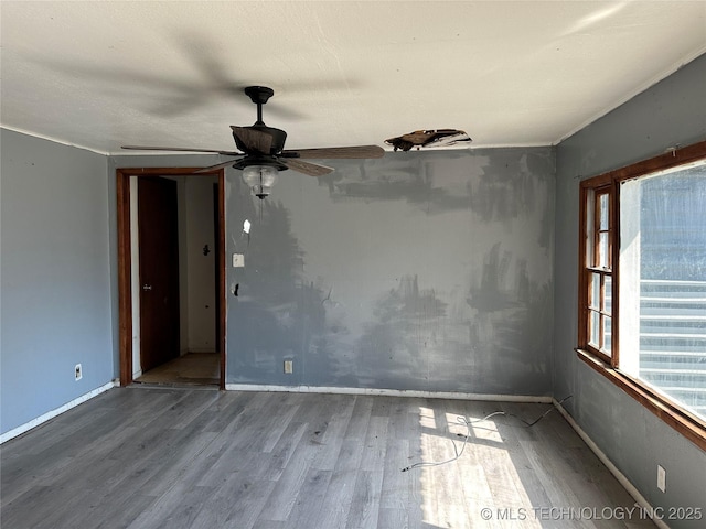 spare room featuring baseboards, wood finished floors, and ceiling fan