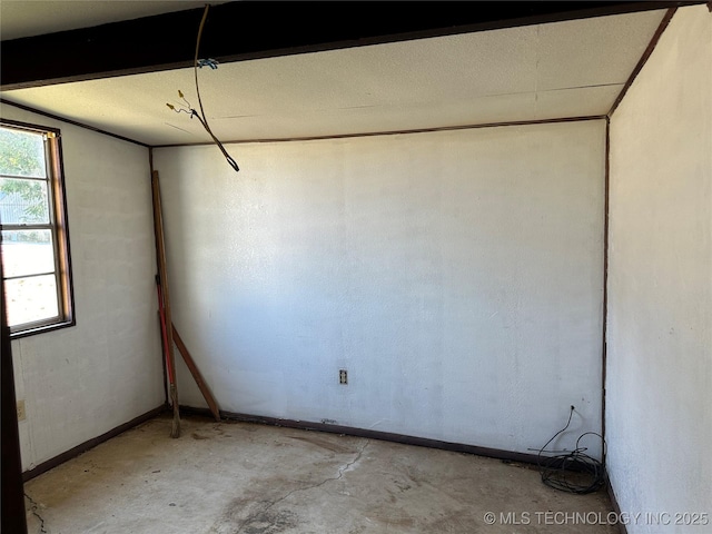 spare room featuring unfinished concrete flooring and baseboards