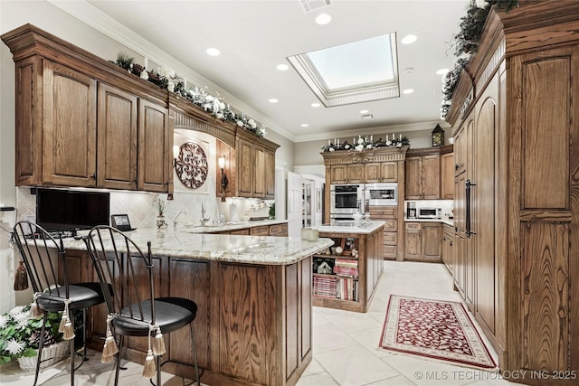 749 Brookhollow Ln, Bartlesville, OK 74006 - kitchen featuring a peninsula, stainless steel microwave, tasteful backsplash, a skylight, and ornamental molding