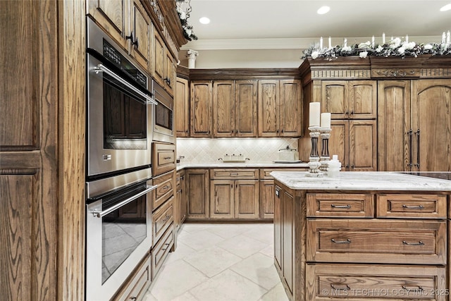 749 Brookhollow Ln, Bartlesville, OK 74006 - kitchen with backsplash, brown cabinets, ornamental molding, and light stone counters