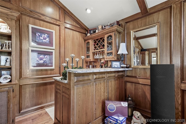 749 Brookhollow Ln, Bartlesville, OK 74006 - bar featuring lofted ceiling, wood walls, a bar, and light wood-style floors