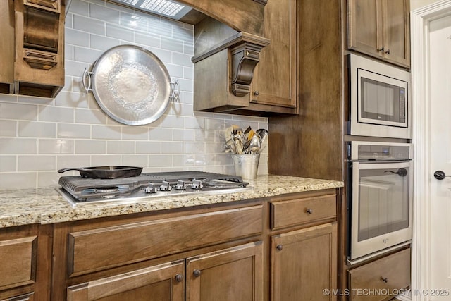 929 S 71st St, Broken Arrow, OK 74014 - kitchen featuring appliances with stainless steel finishes, tasteful backsplash, brown cabinets, and light stone counters
