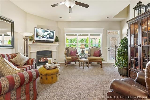929 S 71st St, Broken Arrow, OK 74014 - carpeted living area with ceiling fan, a warm lit fireplace, and baseboards