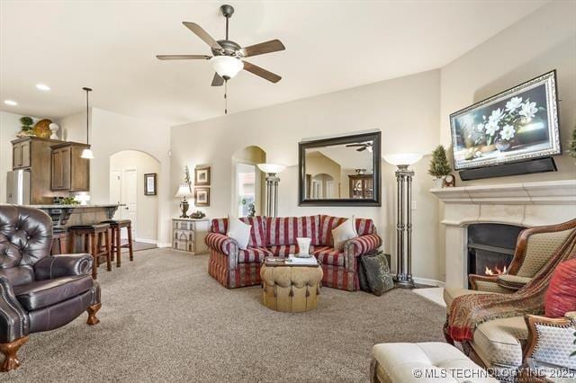 929 S 71st St, Broken Arrow, OK 74014 - living room with arched walkways, ceiling fan, carpet flooring, a warm lit fireplace, and baseboards
