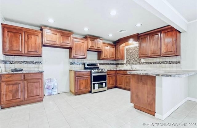 kitchen with visible vents, decorative backsplash, range with two ovens, a peninsula, and brown cabinetry